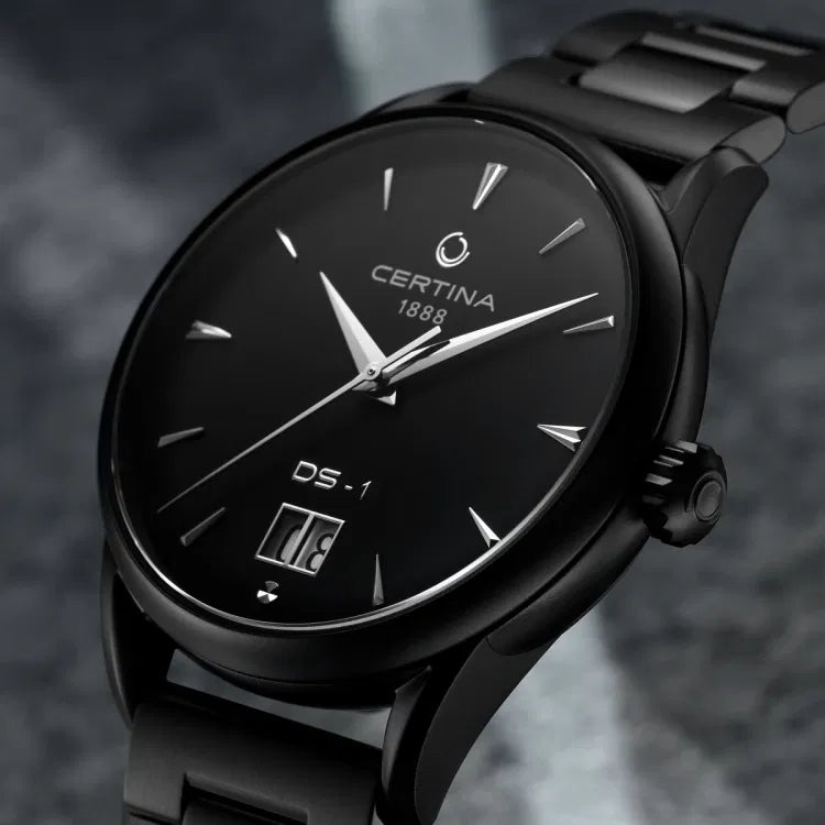 Close-up side view of the Certina DS-1 Big Date Powermatic 80 watch, showcasing its black sunray dial with silver-tone hour markers, ‘CERTINA 1888’ logo, ‘DS-1’ label, and large date window at 6 o’clock. The case and bracelet feature a full black PVD coating.
