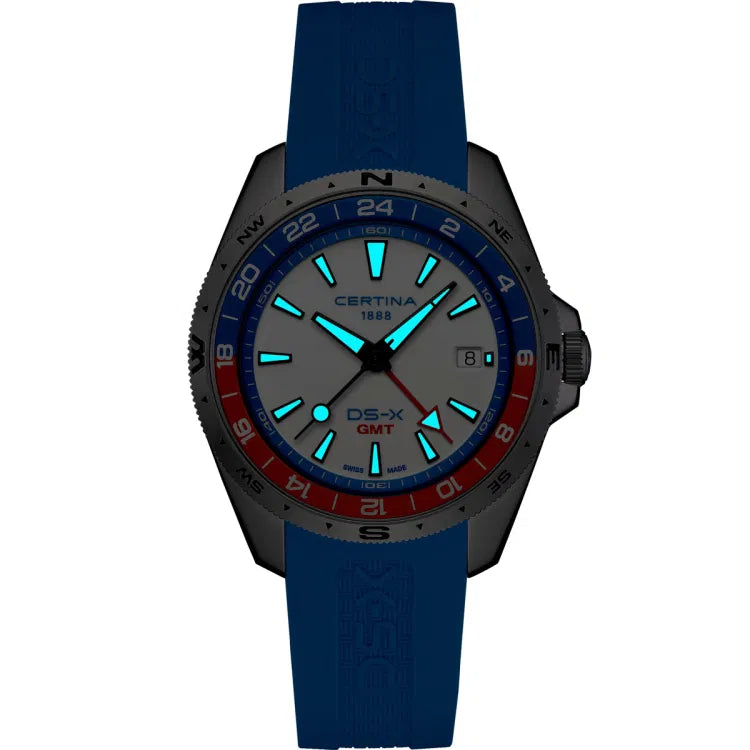 Certina DS-X GMT C047.452.17.011.00 with blue rubber strap glowing in the dark – luminous hands and indices with Superluminova, white dial, red-blue GMT bezel, Certina 1888 and Swiss Made visible.
