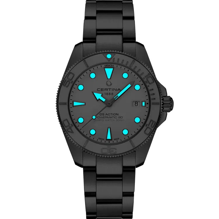 Darkened view of the Certina DS Action Diver 40.5mm watch with glowing blue Super-LumiNova® hands and indices on a white dial. The ceramic bezel and stainless steel bracelet appear in low light. Visible inscriptions on the dial include “CERTINA 1888,” “DS ACTION,” “POWERMATIC 80,” and “DIVER’S WATCH 300m,” with a date window at 3 o’clock.
