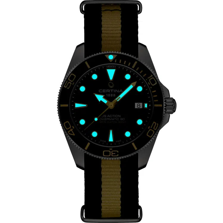 Night view of the Certina DS Action Diver 40.5mm watch with glowing blue Super-LumiNova® markers and hands on a black dial. The black ceramic bezel and black-and-beige NATO strap are visible in low light. Inscriptions on the dial include “CERTINA 1888,” “DS ACTION,” “POWERMATIC 80,” and “DIVER’S WATCH 300m,” with a date window at 3 o’clock.