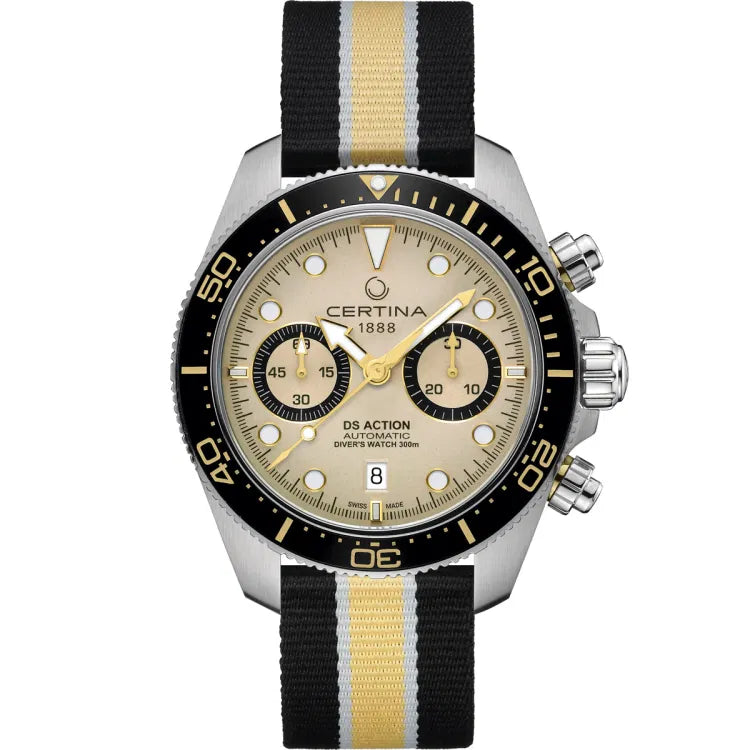 The Certina DS Action Diver Chrono (C032.827.18.271.00) displayed from the front, featuring a beige dial with gold-tone accents, two black subdials, and a date window at 6 o’clock. The black unidirectional ceramic bezel has gold-tone markings for precise dive timing. The stainless steel case is equipped with pushers and a screw-down crown on the right side for enhanced water resistance. The watch is fitted with a black, yellow, and white striped textile NATO strap, complementing its sporty and rugged aesthe